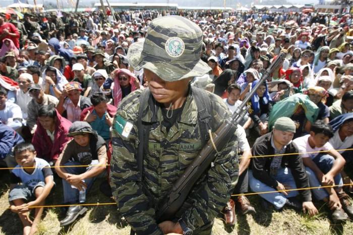 A member of the Philippines' largest Islamic rebel group Moro Islamic Liberation Front stand on guard in front of supporters inside the guerrilla base during the central committee hearing at the southern island of Mindanao, March 11, 2008.
