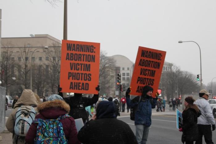 Activists hold up signs warning participants of graphic pictures of what abortion does to human fetuses that were displayed on large screens a long the path of the March for Life in Washington, D.C. on Jan. 22, 2016.
