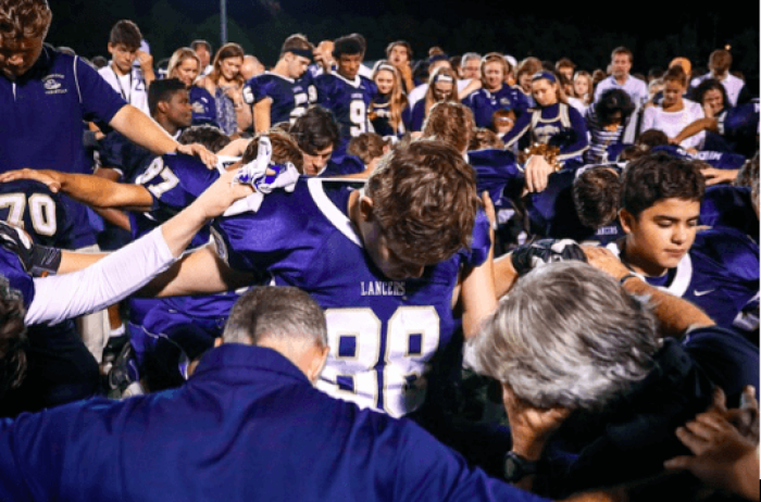 Cambridge Christian School students in Florida pray at a high school football game.