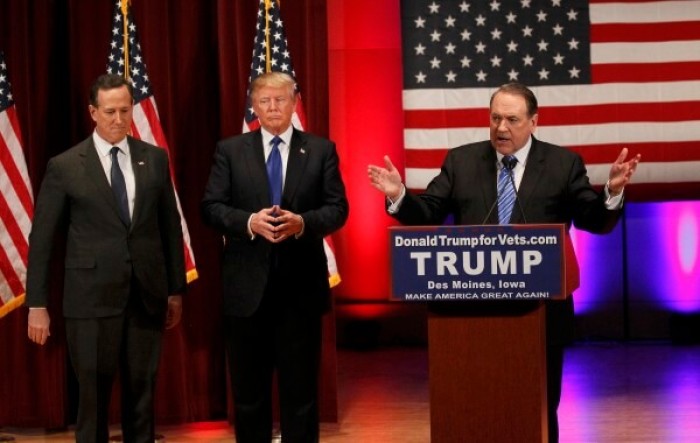 Republican presidential candidate Donald Trump (center) and rival candidate Rick Santorum listen as fellow candidate Mike Huckabee speaks at a fundraising event for veterans at Drake University in Des Moines, Iowa on Thursday January 28, 2016.