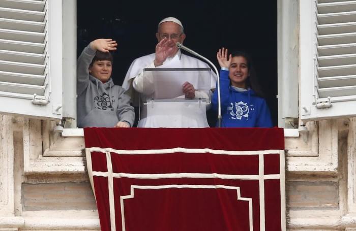 Pope Francis waves with two children as he leads his Angelus prayer at Saint Peter's Square in the Vatican, January 31, 2016.