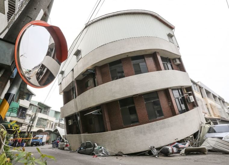 Crushed vehicles are seen under a building that was damaged after a powerful earthquake hit Tainan, February 6, 2016.