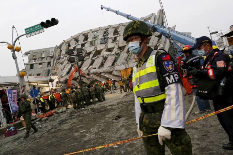 A soldier stands guard in front of a collapsed building after an earthquake hit Tainan, southern Taiwan, February 6, 2016.