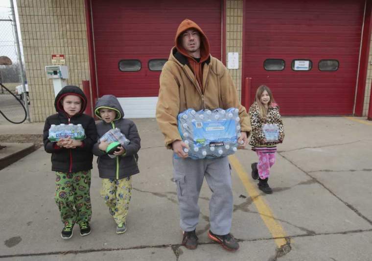 Flint resident Jerry Adkisson (2nd R) and his children Jayden (L), Austin and Amiya carry bottled water they picked up from a fire station in Flint, Michigan February 7, 2016.