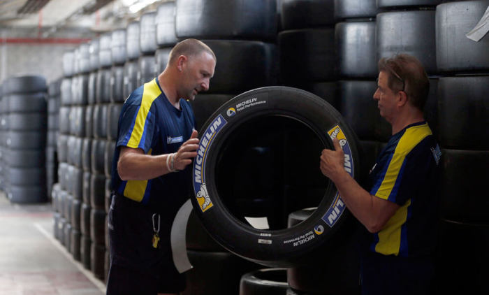 Workers hold a motorsport racing tyre stocked in the Michelin tyre company's factory in Clermont-Ferrand, central France, July 10, 2013. Picture taken July 10, 2013.
