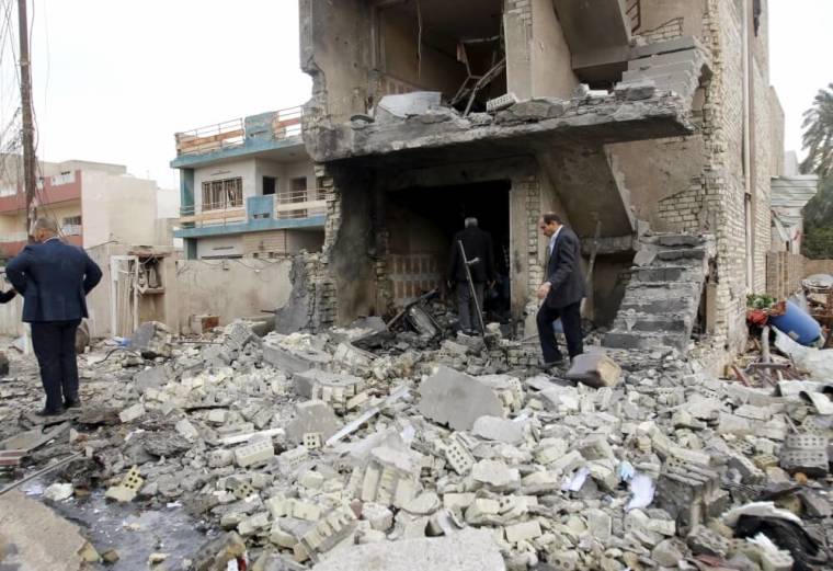 Residents inspect the site of a car bomb blast in New Baghdad, January 12, 2016.