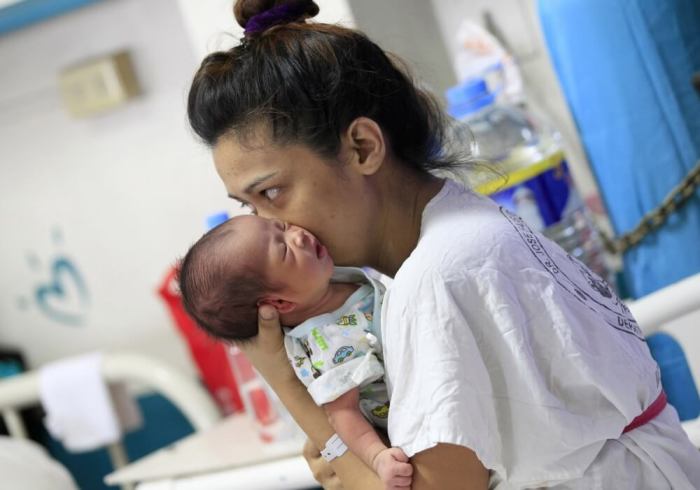 A mother kisses her newborn baby while resting inside the Fabella hospital dubbed as the busiest maternity hospital in the country, in Manila, Philippines, February 16, 2016. A minister in the Philippines has urged women to delay pregnancy until more is known about the mosquito-borne Zika virus raging in Latin America, even though the Asian country's only reported case of zika was four years ago.