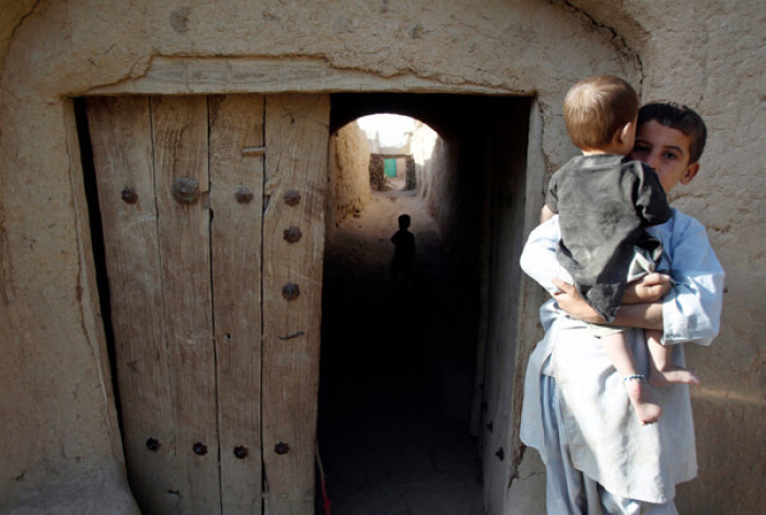 An Afghan boy holds a baby as U.S. , Canadian and Afghan soldiers give away school supplies, donated by a school in Canada, in the village of Small Loi Kola in the Panjwai district of Kandahar province southern Afghanistan, June 23 , 2011.