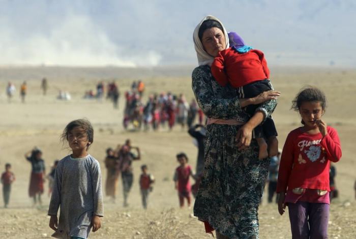 Displaced residents from the minority Yazidi sect, fleeing violence from Islamic State forces in Sinjar town, walk towards the Syrian border, on the outskirts of Sinjar mountain, near the Syrian border with Iraq, August 11, 2014.