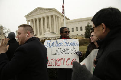 Supporter Anthony Lecounte holds a sign praising the late U.S. Supreme Court Justice Antonin Scalia as the casket containing his remains arrived at the Supreme Court to lie in repose in the building's Great Hall in Washington, February 19, 2016. Scalia died on February 13, 2016 at the age of 79.