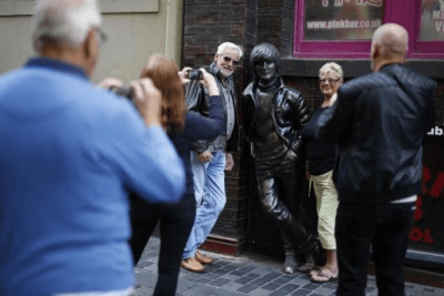 Tourists pose for photographs next to a statue of John Lennon in Liverpool northern England, Britain, August 16, 2015.
