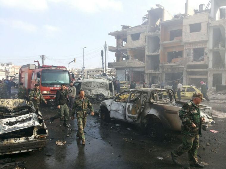 Syrian army soldiers inspect the site of a two bomb blasts in the government-controlled city of Homs, Syria, in this handout picture provided by SANA on February 21, 2016.