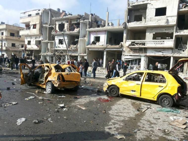 Syrian army soldiers and civilians inspect the site of a two bomb blasts in the government-controlled city of Homs, Syria, in this handout picture provided by SANA on February 21, 2016.