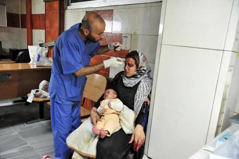 wounded woman carries a baby as she receives treatment inside a hospital after multiple bomb blasts hit a southern district of Damascus, Syria, in this handout picture provided by SANA on February 21, 2016.