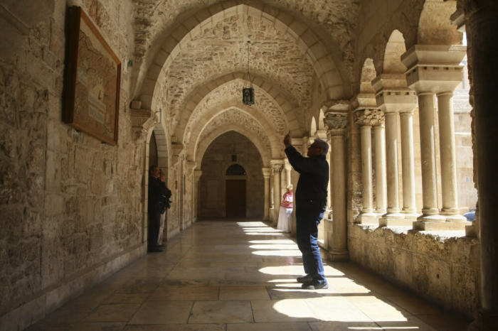 A tourist takes a picture with his mobile phone inside the Church of the Nativity in the West Bank town of Bethlehem May 19, 2014. When Pope Francis visits the birthplace of Jesus next week, he will address a dwindling population of faithful whose exodus from the Holy Land could turn the shrines of Christendom into museum pieces. Picture taken May 19, 2014.