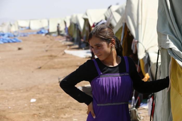 A displaced girl from the minority Yazidi sect, who fled the violence in the Iraqi town of Sinjar, stands at Nowruz refugee camp in Qamishli, northeastern Syria on the border with Kurdistan, August 16, 2014.