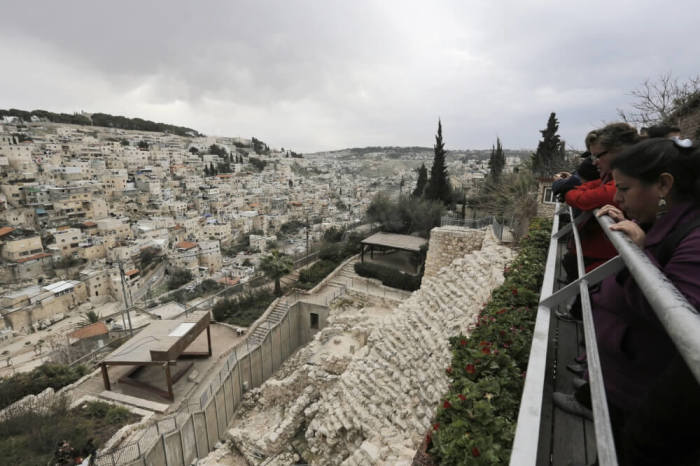 Visitors tour the archaeological site known as the City of David, situated just outside the Old City in East Jerusalem, opposite the mostly Arab East Jerusalem neighborhood of Silwan (L), January 26, 2014.