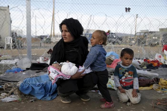 A migrant who is waiting to cross the Greek-Macedonian border, rests with her children at a makeshift camp near the village of Idomeni, Greece, March 8, 2016.