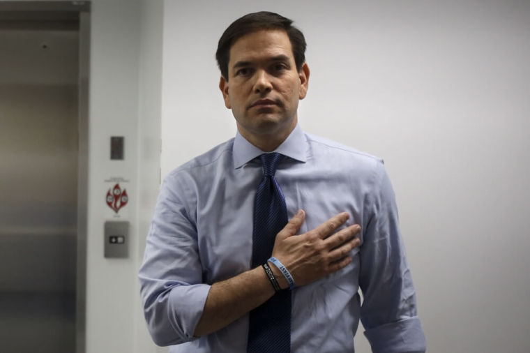 U.S. Senator and Republican presidential candidate Marco Rubio holds his hand over his heart in a backstage area as the pledge of allegiance is recited before a campaign rally at Palm Beach Atlantic University in West Palm Beach, Florida, March 14, 2016.