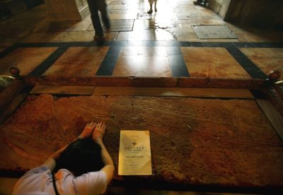 A Christian pilgrim prays at the large marble slab traditionally believed to be the stone that Jesus Christ's body was washed upon when removed from the cross, in the Church of the Holy Sepulcher, Jerusalem, Israel, June 6, 2006