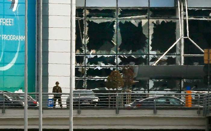A soldier stands near broken windows after explosions at Zaventem airport near Brussels, Belgium, March 22, 2016.