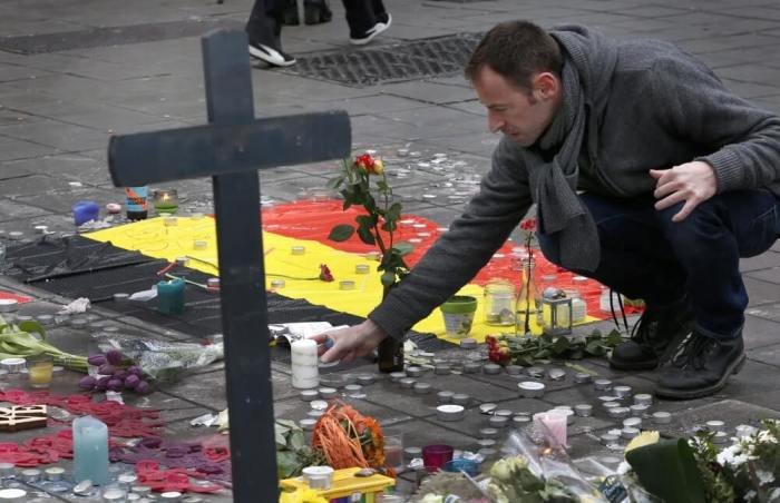 A man places flowers on a street memorial following Tuesday's bomb attacks in Brussels, Belgium, March 23, 2016.