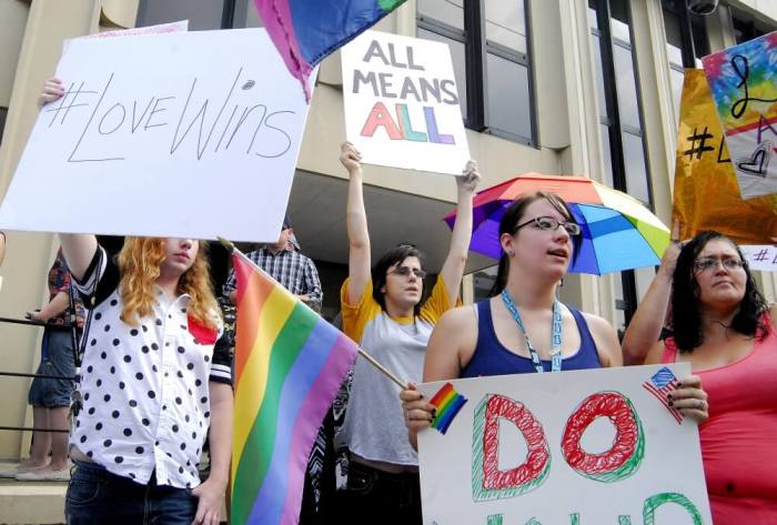 Demonstrators stand on the front steps of the federal building waving a rainbow flag in protest of Rowan County clerk Kim Davis' arrival to attend a contempt of court hearing for her refusal to issue marriage certificates to same-sex couples at the United States District Court in Ashland, Kentucky, September 3, 2015.