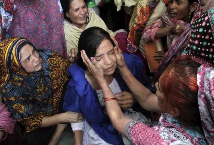 Family members comfort a woman mourns the death of a relative, who was killed in a blast outside a public park on Sunday, during funeral in Lahore, Pakistan, March 28, 2016.