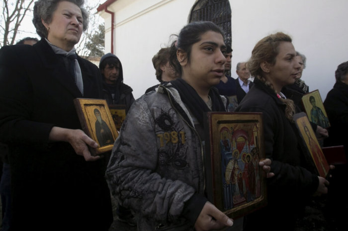 Christian Orthodox Iranian migrants Roya (C) and Sami (R), who live for twenty days at a makeshift camp for refugees and migrants, hold icons during a mass marking the Sunday of Orthodoxy at the church of the village of Idomeni, Greece, March 20, 2016.