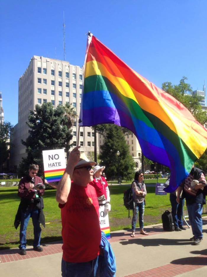An LGBT activist holds up a rainbow flag outside California's state capitol building in Sacramento, while leading evangelist Franklin Graham holds a prayer rally on March 31, 2016.