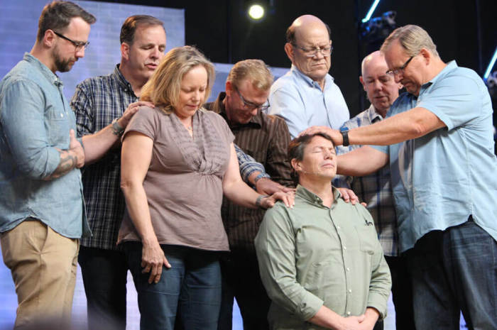 Pastor Rick Warren (far right) prays and dedicates Danny Duchene (kneeling) as pastor for Saddleback Church's prison ministries on Saturday, April 2, 2016. Duchene was released from California's prison after serving 32 years of a double life sentence and shared his testimony at Saddleback Church during his dedication service. Duchene was released on parole at the request of Pastor Rick Warren to California's governor.