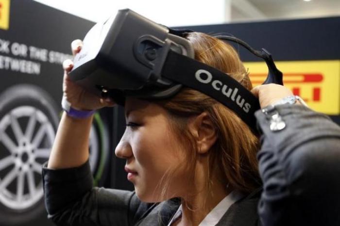 A woman is seen here putting on an earlier version of the Oculus virtual reality headset during the 2014 LA Auto Show.