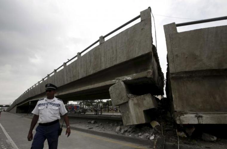An Ecuadorian police officer stands beside a collapsed bridge after a quake hit the coastal province in the country.