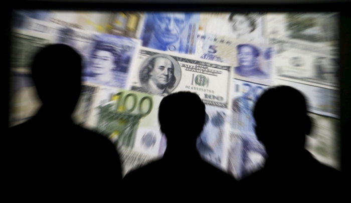 People are silhouetted against a backdrop projected with the picture of various currencies of money in this illustration taken April 4, 2016.
