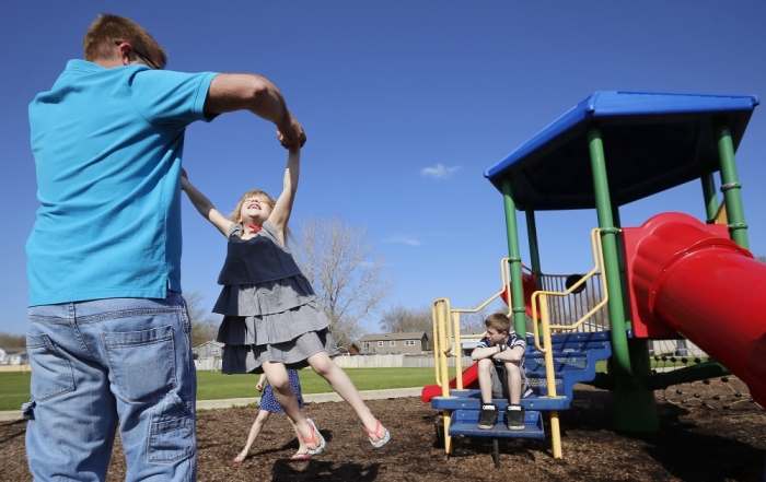 Joe Smith plays with his daughter Norah as his son Chase looks on at a playground in Winthrop Harbor, Illinois, May 9, 2014.
