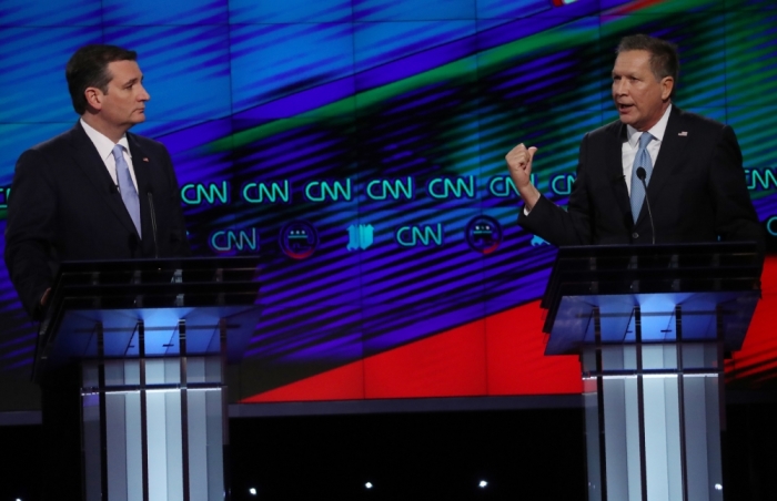 Republican U.S. presidential candidate Ted Cruz (L) listens to rival John Kasich during the Republican U.S. presidential candidates debate sponsored by CNN at the University of Miami in Miami, Florida March 10, 2016.