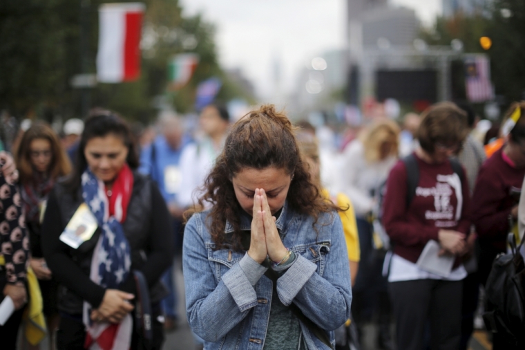 A woman prays during mass with Pope Francis on the Benjamin Franklin Parkway in Philadelphia, Pennsylvania September 27, 2015.