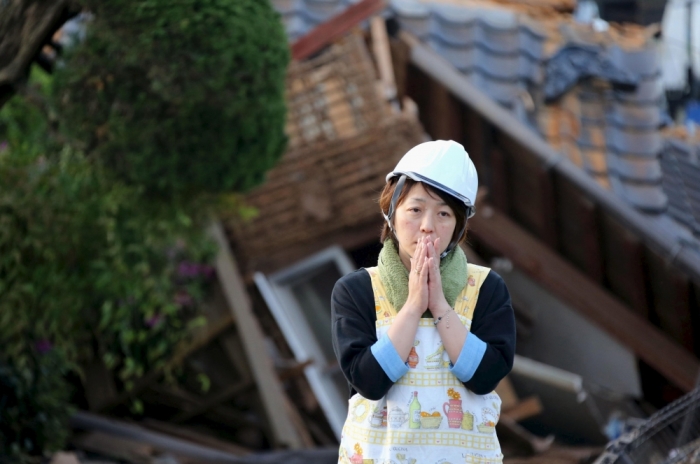 A woman reacts in front of collapsed house caused by an earthquake in Mashiki town, Kumamoto prefecture, southern Japan, in this photo taken by Kyodo, April 16, 2016.