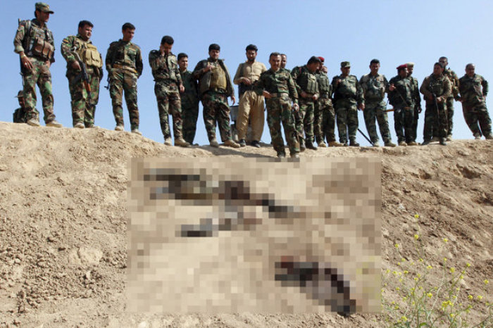 A group of Kurdish fighters stare at the dead suicide bombers in this undated photo.