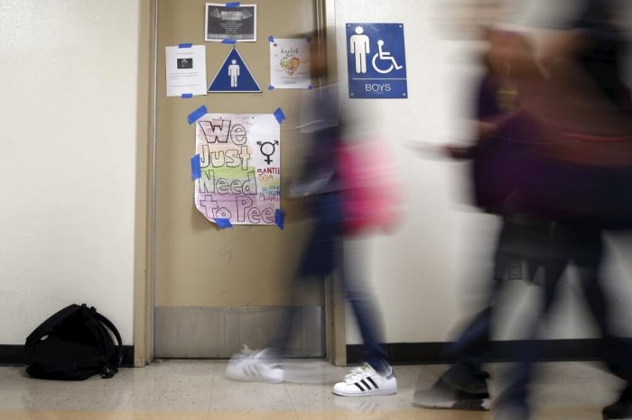 Students walk past a protest sign on a bathroom which helped lobby for the first gender-neutral restroom in the Los Angeles school district at Santee Education Complex high school in Los Angeles, California, U.S., April 18, 2016.