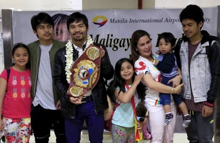 Filipino boxing champion Manny Pacquiao poses with his family while showing his WBO championship belt to the media, after defeating Timothy Bradley, upon his arrival at the Ninoy Aquino International Airport in Manila, Philippines, April 14, 2016.