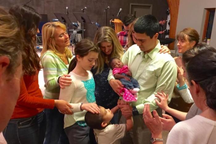 Friends gather to pray over the family's new adopted baby girl.
