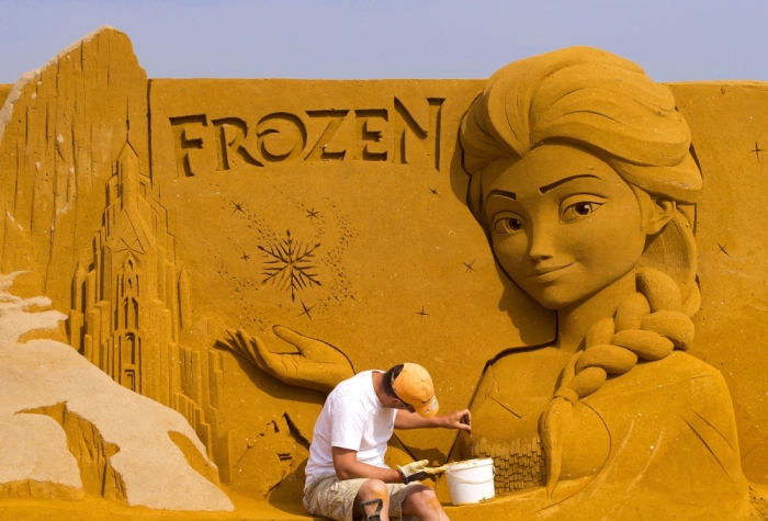 A sand carver works on a sculpture during the Sand Sculpture Festival 'Frozen Summer Fun' in Ostend, Belgium June 12, 2015. A team of 30 carvers from around the world spent four weeks building 150 giant sculptures based on Marvel, Star Wars, Disney and Pixar movies.
