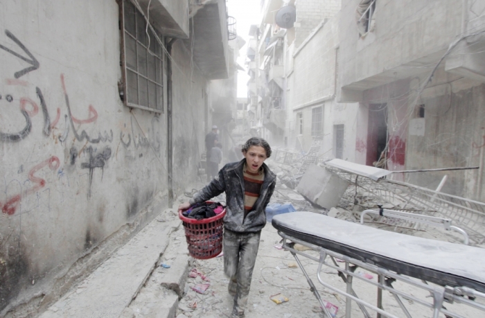 A boy carries his belongings at a site hit by what activists said was a barrel bomb dropped by forces loyal to Syria's President Bashar al-Assad in Aleppo's al-Fardous district, Syria April 2, 2015.