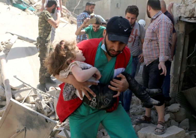 A civil defence member carries a child that survived from under the rubble at a site hit by airstrikes in the rebel held area of Old Aleppo, Syria, April 28, 2016.