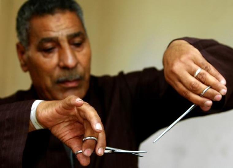 Egyptian barber Hassan Hafez mimics his procedure for performing female genital mutilation in this 2006 photo.