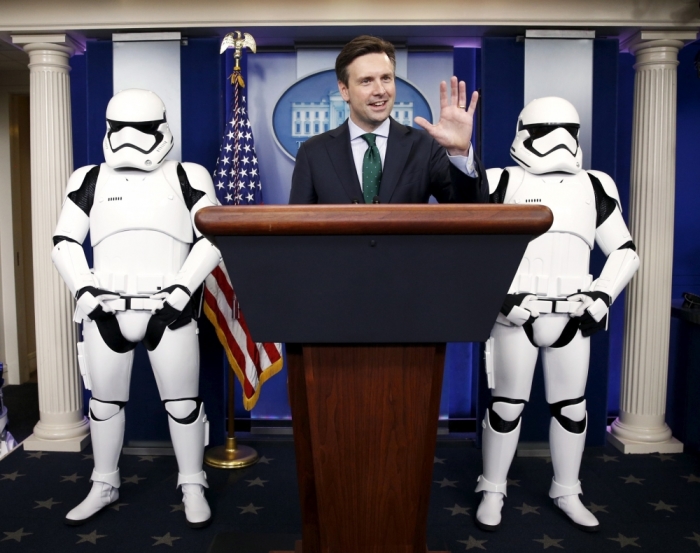 White House Press Secretary Josh Earnest appears in the briefing room with Star Wars Stormtroopers and Robot R2-D2 (L) after Obama finished his end of the year news conference at the White House in Washington, December 18, 2015.