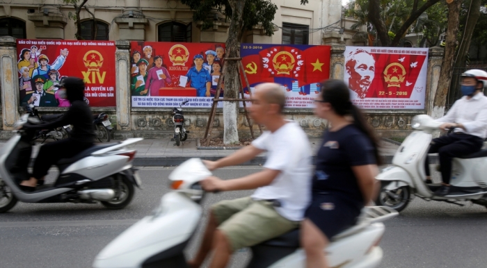 People drive past posters promoting the 14th National Assembly election outside Nhan Dan daily, the Vietnam Communist Party's paper, on a street in Hanoi, Vietnam May 20, 2016.