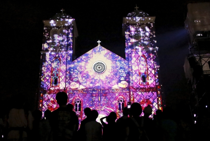 People look at a computer graphic video, using projection-mapping technology, beamed on the Urakami Cathedral, which was destroyed by the atomic bombing of Nagasaki on August 9, 1945 and rebuilt in 1959, in Nagasaki, western Japan, August 8, 2015, on the eve of the 70th anniversary of the bombing of Nagasaki. Japan will mark on Sunday the 70th anniversary of the attack on Nagasaki, where the U.S. dropped a second atomic bomb on August 9, 1945, which killed about 40,000 instantly.