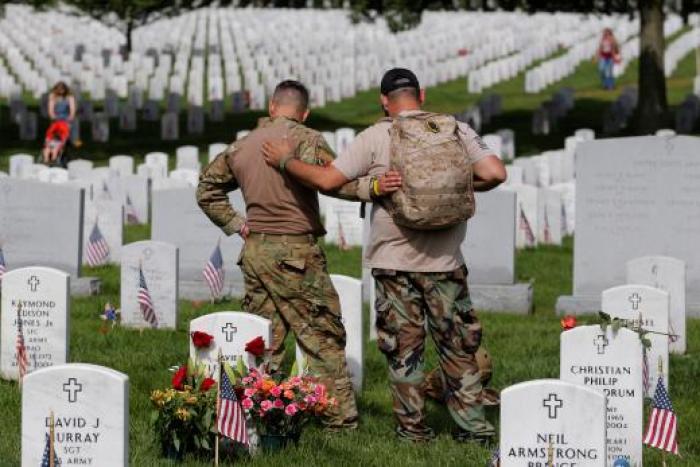 U.S. Army soldiers Rick Kolberg (L) and Jesus Gallegos embrace as they visit the graves of Raymond Jones and Peter Enos on Memorial